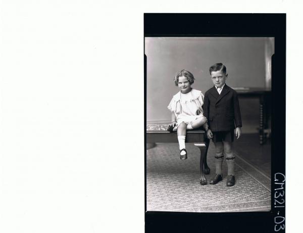 F/L Portrait of boy standing wearing shorts, shirt, tie and jacket, girl seated wearing short lace dress; 'Mullins'