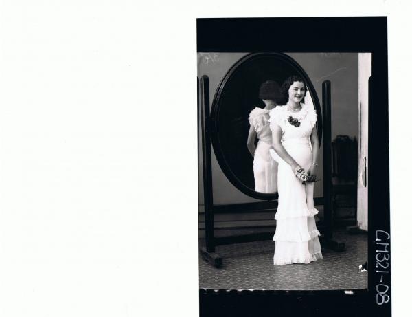 F/L Portrait of woman standing in front of mirror wearing frilly evening dress; 'McFatty'