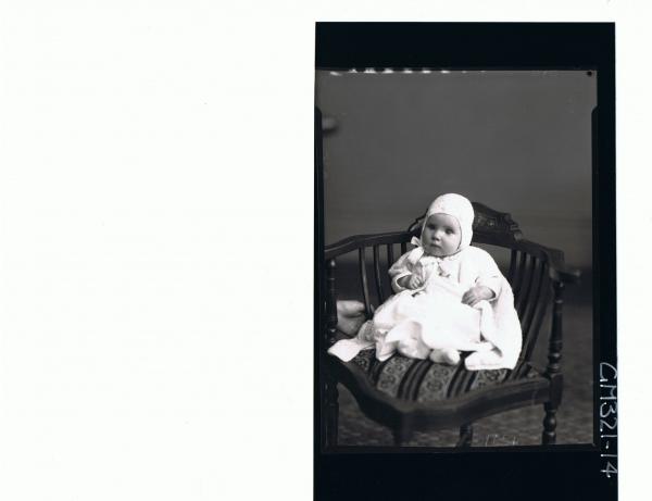 F/L Portrait of baby seated wearing dress, knitted jacket and bonnet; 'Madill'