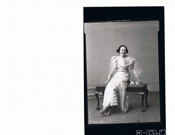 F/L Portrait of woman seated wearing long frilly evening dress; 'Mills'