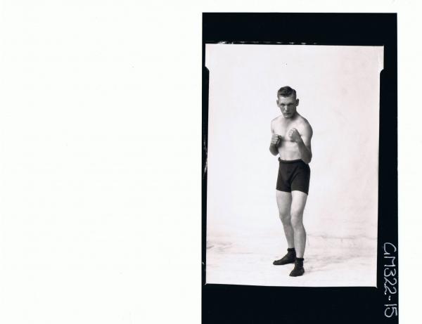 F/L Portrait of man standing in boxing position, wearing boxing shorts and shoes; 'Trembath'