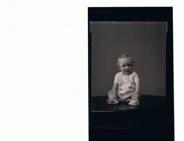 F/L Portrait of baby seated on table, wearing short lace dress; 'Spalholtz'