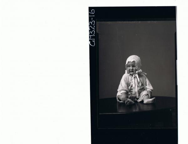 F/L Portrait of baby seated on table, wearing short dress, cardigan and bonnet; 'Spalholtz'