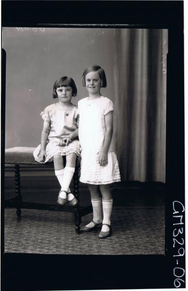 F/L Portrait of girl standing wearing short frilly dress, girl seated wearing similar dress; 'Boyland'