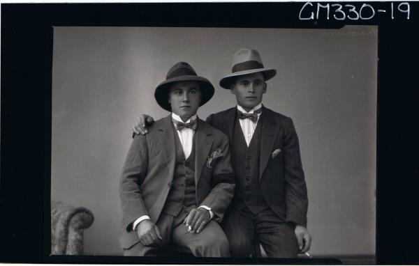 1/2 Portrait of two young men seated, wearing three piece suit, bow ties, hats, holding cigarettes; 'Maccasini'