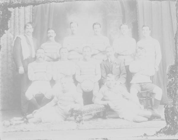 Group portrait of soccer team 'Premiers 1910 B.C.F.C.' written on ball.