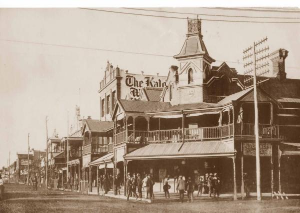 Exchange Hotel, corner of Hannan Street and Maritana St looking up towards Mt Charlotte.  Several men and boys standing outside, Hocking (Kalgoorlie Miner) building in background.  1900