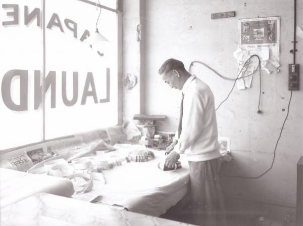 Japanese laundry, Japanese man ironing in front of shop window with an electric iron.