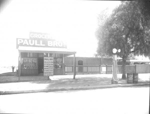 Paull Bros Grocery store, house attached, petrol pump on stree verge.  Advertising sign outside and large tree.