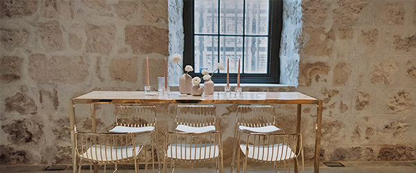 Image showing metallic table with flowers, candlesticks and chairs set up in front of window and old feature brick wall