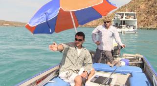 Rodrigo on a small dingy with using the Darlek to capture information from the sea under an umbrella