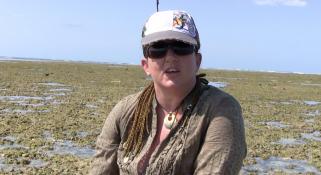 Zoe Richards wearing a hat and sunglasses talking about the corals on a reef