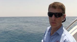 Dr Glenn Moore fishing from the back of the Kimberley Quest boat wearing sunglasses