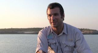 A boat skipper seated on the bow of a ship