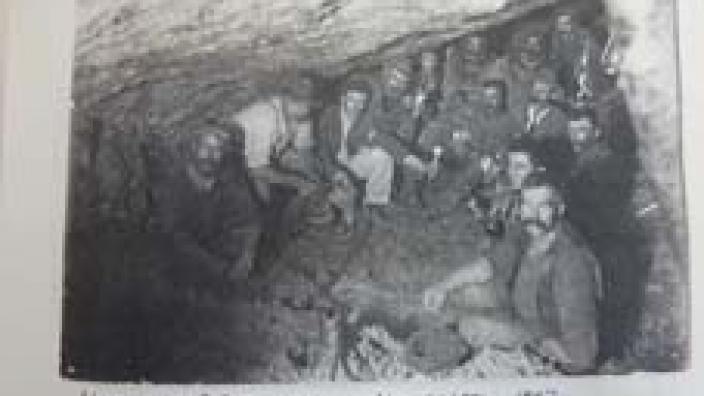 Members of rescue team in mine shaft feeding through air hose and life line.