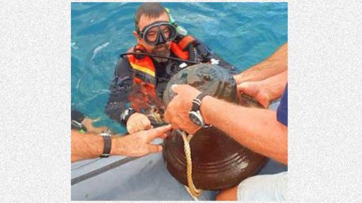 Diver returning a bell to the deck of a ship