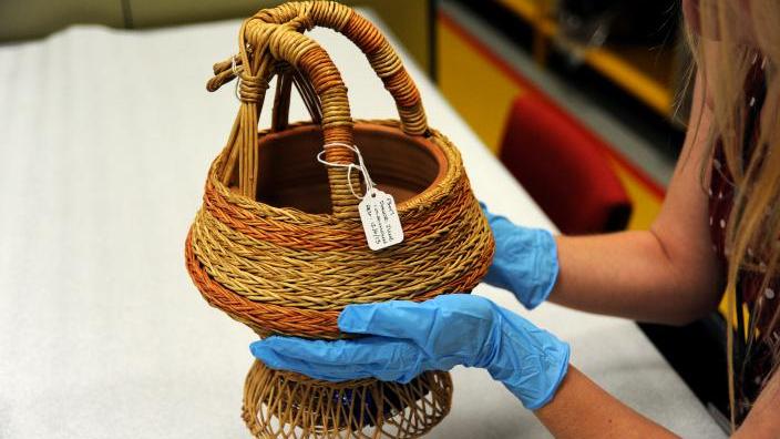 Anthropology staff inspecting a Kangri basket.