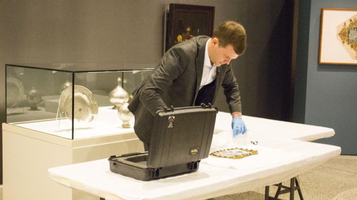 Curator Ben van den Burcken carefully unpacks the cameo for installation