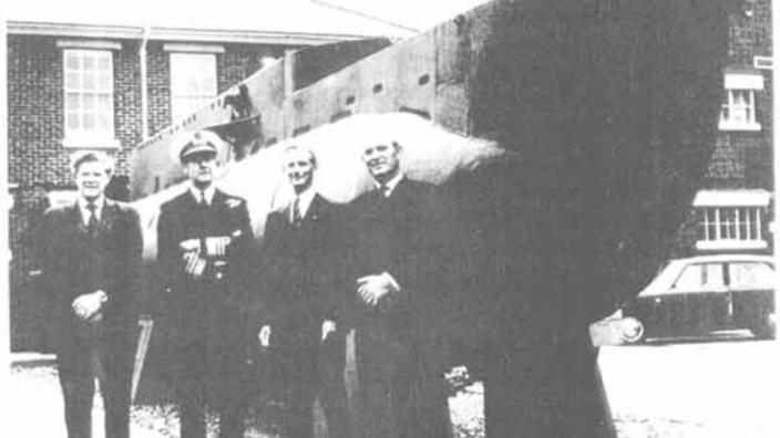 Several people standing in front of a moored submarine