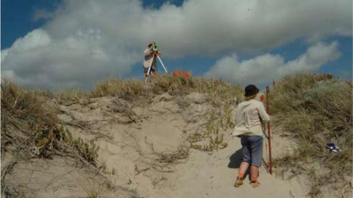 Two people performing surveys on the beach