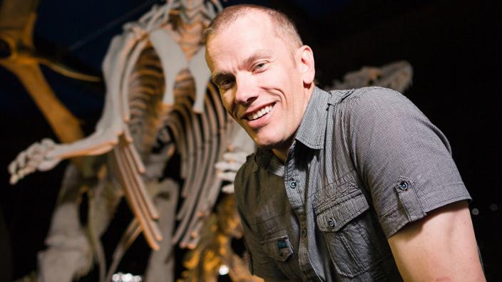 Dr Mikael Siversson standing alongside a dinosaur cast