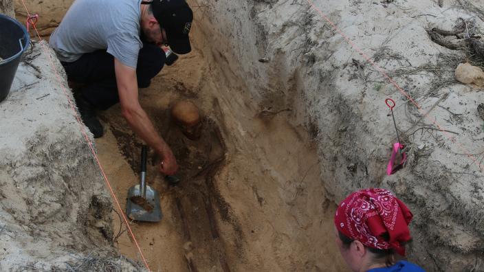 Two researchers carefully excavating a burial site at Beacon Island, 2015