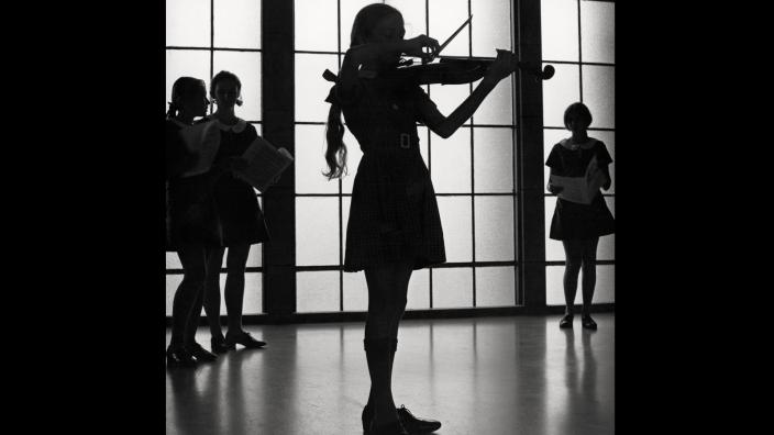 A silhouette of a child playing violin