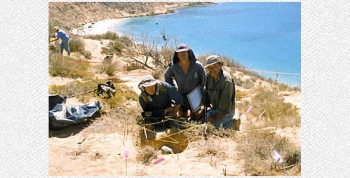 Three scientists posing near an excavation site
