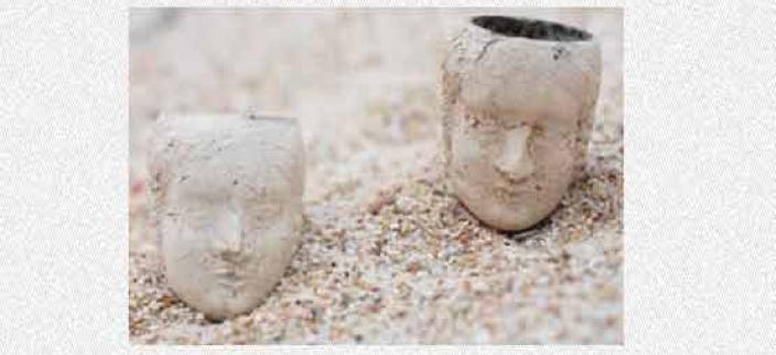 Two decorated tobacco bowls on a sandy beach