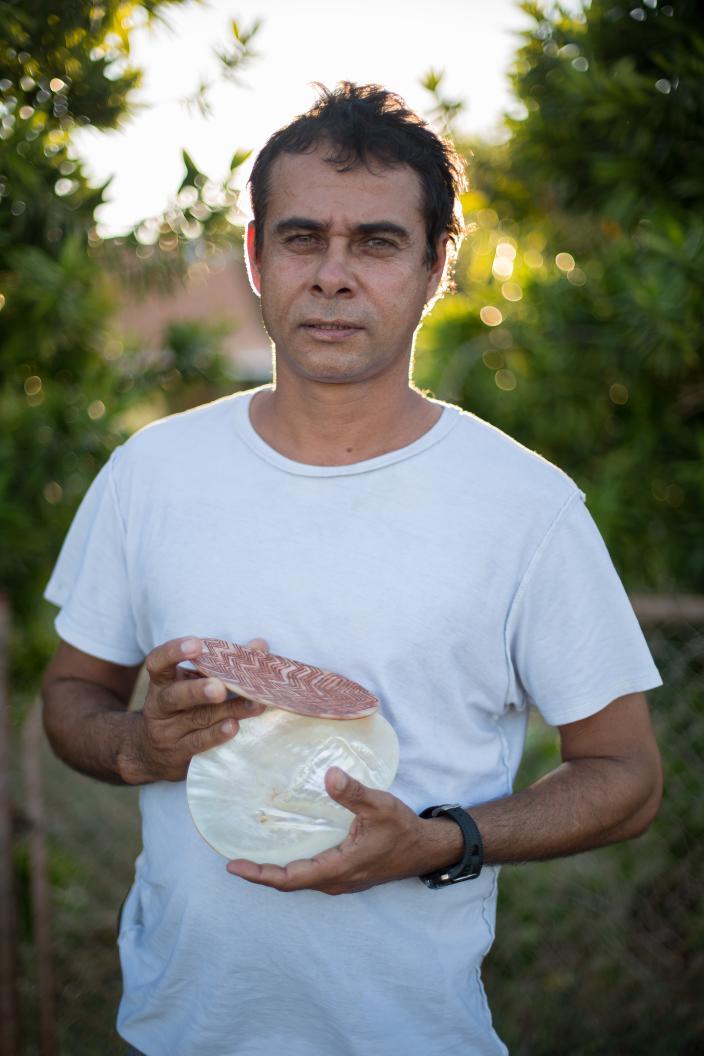 Image of a man holding a carved pearlshell.