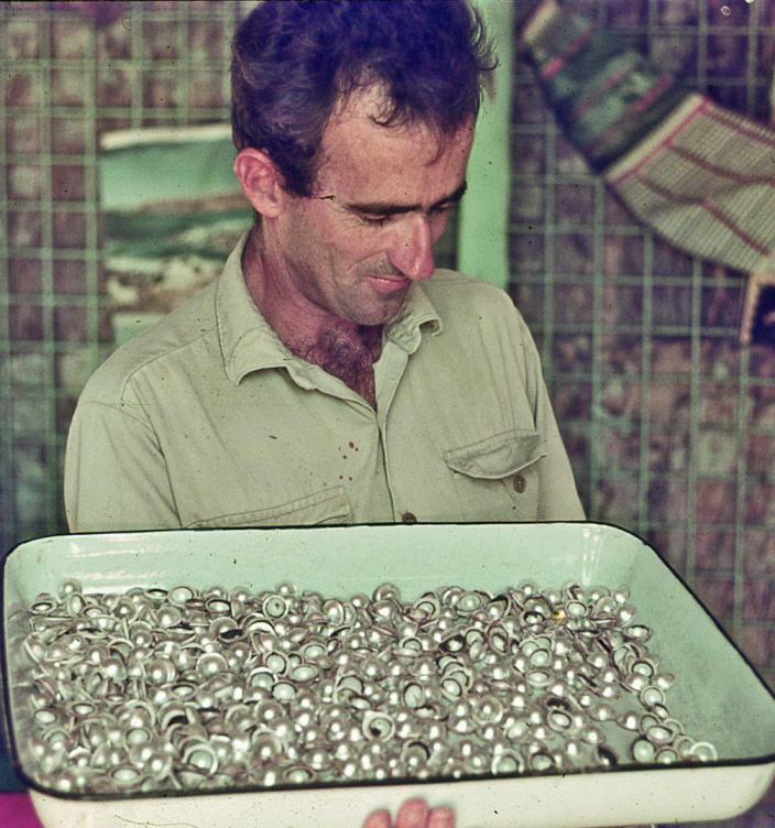 A man holding a tray of pearls. 