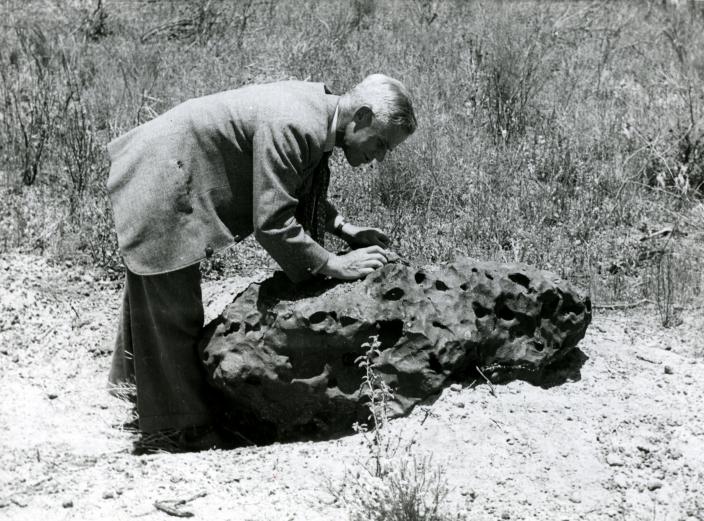 Image of a man inspecting a large meteorite