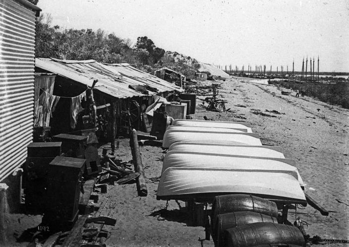 An image of dinghies upturned on a beach. 