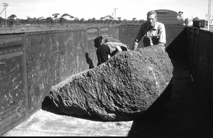 Image of two men standing next to a massive meteorite