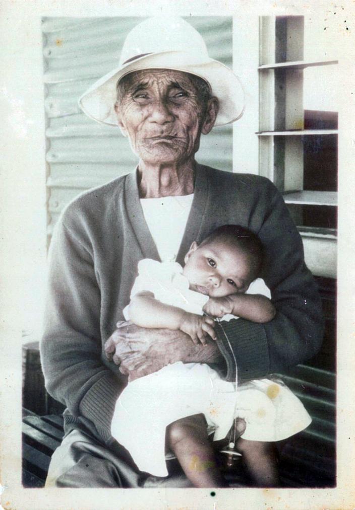 Image of an elderly man holding a baby. 