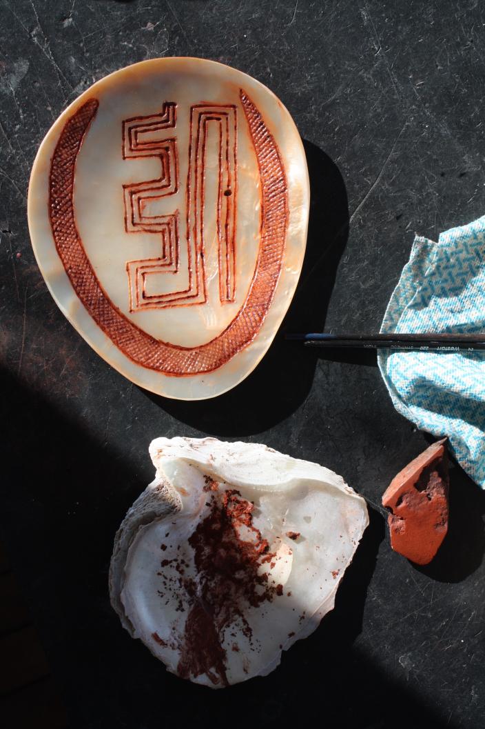 An image of a work bench with pearlshell and red ochre. 