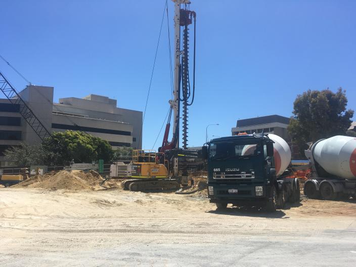 construction site, a large truck in the foreground and a very tall large drill