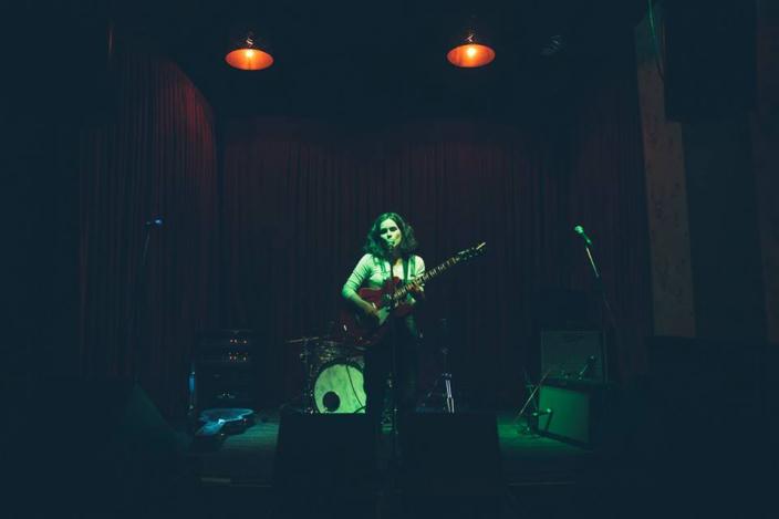 Grace singing and playing the guitar on stage