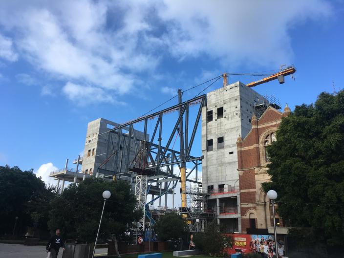 "Construction site showing large metal structural beams against a blue sky."