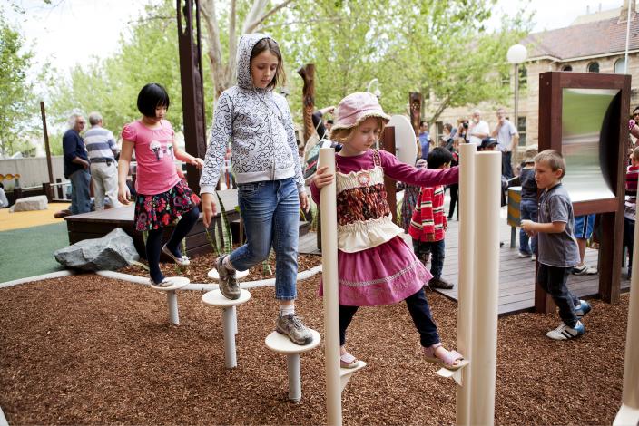 Children walking on stilt-like equipment in a play space