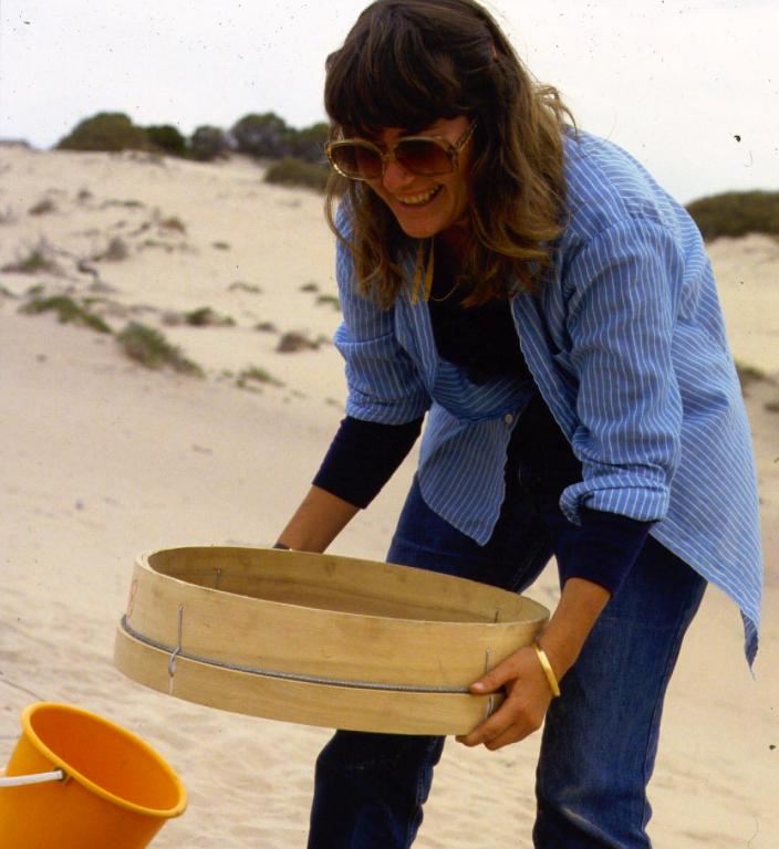 "A woman is sifting through sand during an archaeological dig."