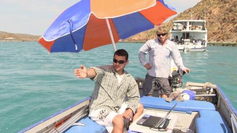 Rodrigo on a small dingy with using the Darlek to capture information from the sea under an umbrella