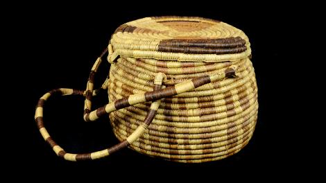 A large round lidded basket with a double handle and a woven latch.