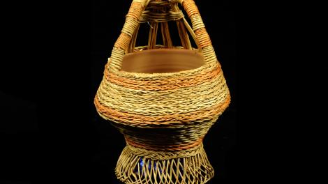 A natural and red/orange basket. It has a hollow base that angles upwards.