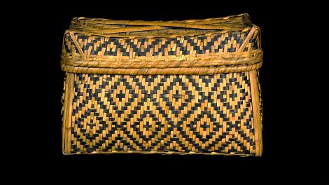 A lidded, rectangular, black and natural coloured basket  with a diamond design.