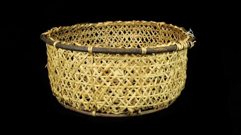 A straight sided and round basket made from split bamboo with a willow rim.