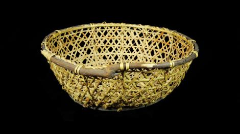 A round basket with sloping sides. It is made frosplit bamboo with a willow rim.