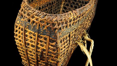 An open wickerwork basket made from split bamboo, rattan and rope straps.