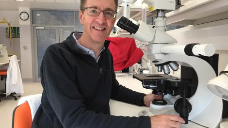 "Dr Mark Harvey working at a microscope"