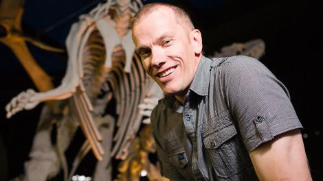Dr Mikael Siversson standing alongside a dinosaur cast